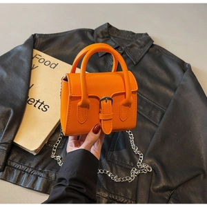 Détail d'un mini sac à main orange vif avec chaîne en métal et boucle vintage