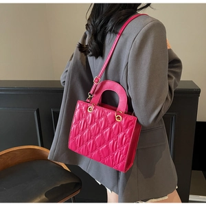 Magenta quilted crossbody bag shown on a model wearing a grey blazer jacket