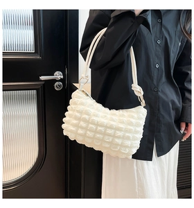 Detail of white bubble texture fabric and knotted shoulder strap on the chic armpit bag
