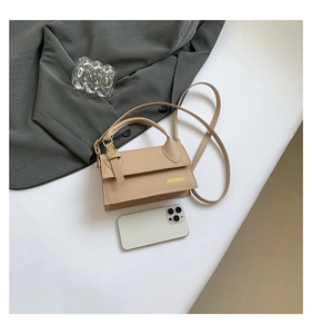 Detail of khaki square handbag on grey blazer with long strap and compact structure