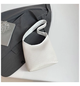 Detail showing white crocodile texture and sleek handle of minimalist crossbody bag