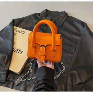 Gros plan d'un mini sac carré en cuir orange avec boucle argentée et chaîne métal