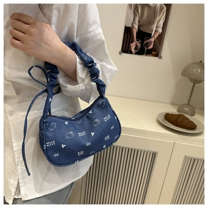 Détail du sac hobo en denim bleu avec imprimés de dessins animés et poignée froncée