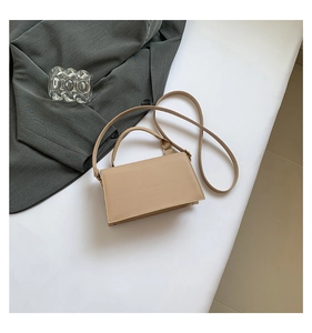 Detail of minimalist khaki square handbag with leather handle and adjustable shoulder strap