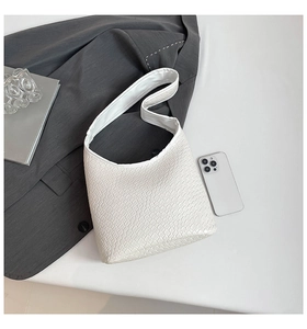 Close-up of white faux crocodile embossed texture on a minimalist half-moon shoulder bag