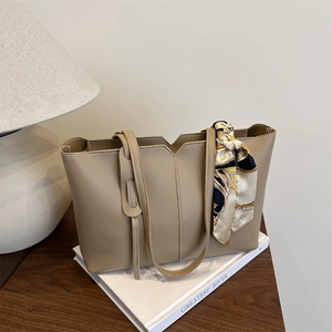 Minimalist beige tote bag with floral scarf handle on a table in a cozy home setting