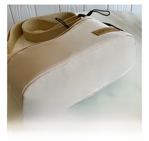 Close-up of beige casual crossbody bag fabric texture and leather brand patch detail