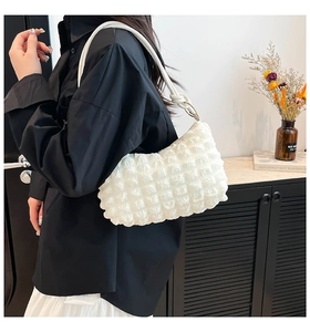 Detail of white bubble textured shoulder bag with chic metal rings and soft pleated strap