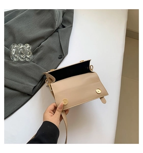 Detail view of the beige square shoulder bag showing gold magnetic snaps and inner lining