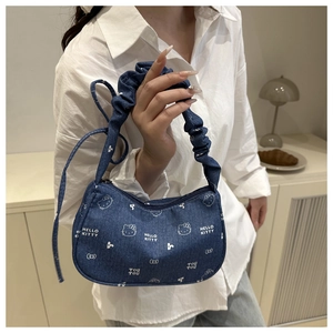Détail du sac à bandoulière en denim bleu avec motifs floraux blancs et anse plissée