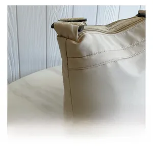 Detailed close-up showing stitching craft and beige nylon texture on the crossbody bag