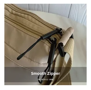 Detail of khaki nylon bag featuring smooth double zippers and black cord pulls