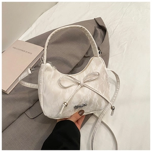 Detail of white marble textured crescent bag with bow decoration and silver logo