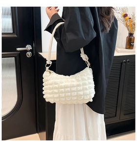 Detail of white bubble texture handbag with knotted shoulder strap and gold ring buckle