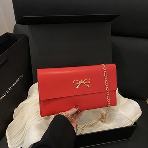 Minimalist red envelope chain bag with gold bow clasp shown in elegant gift packaging
