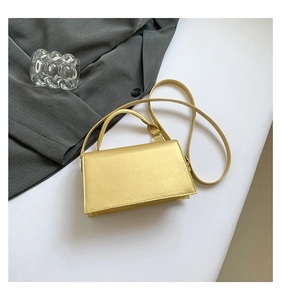 Detailed top view of a gold satin square crossbody bag with handle and slim shoulder strap