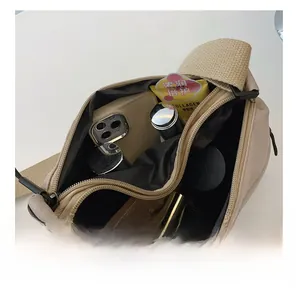 Internal large capacity of beige nylon crossbody bag showing compartments and black lining