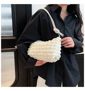 Close-up of white bubble texture shoulder bag with rope strap and metal buckle detail