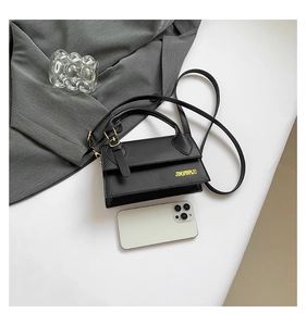 Detail shot of a black square leather bag next to a smartphone showing compact size and texture