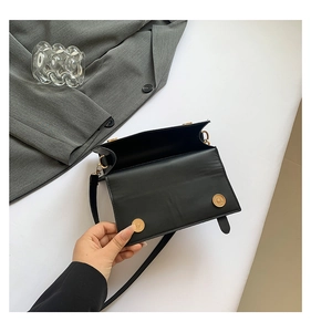 Detail of black leather crossbody bag interior featuring dual gold magnetic closures