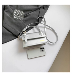 Detailed top view of a silver metallic rectangle handbag with a long shoulder strap