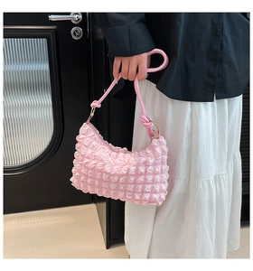 Detail of pink bubble texture handbag featuring soft pleated design and golden hardware