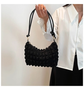 Detail of black pleated bubble texture fabric and stylish knotted handles on underarm bag