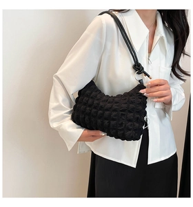 Detail of black bubble texture shoulder bag with metallic ring and decorative knot