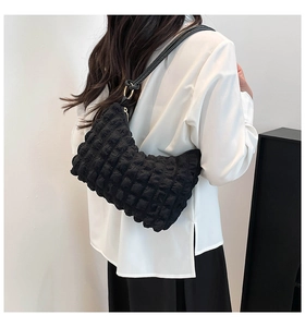 Detail of black pleated cloud shoulder bag showing bubble texture and golden metal ring