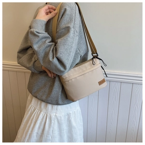 Detail of light khaki nylon crossbody bag with adjustable strap and side logo patch