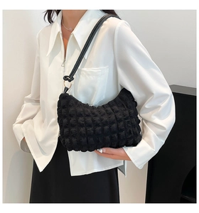 Detail of soft bubble texture and leather strap on this black pleated hobo shoulder bag