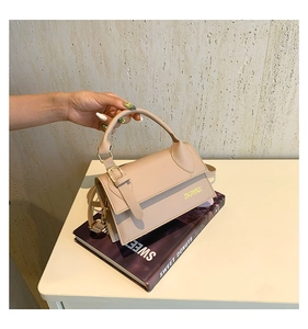 Detail view of the elegant beige flap handbag featuring polished gold buckle and handle