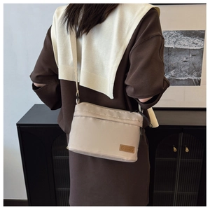 Détail du sac bandoulière en nylon beige avec logo tendance et sangle réglable