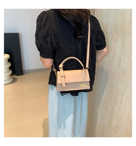 Detail of beige shoulder bag with gold clasp and logo shown on model back view