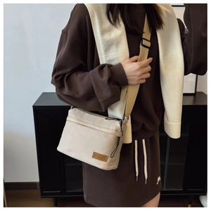Détails de la bandoulière réglable et du patch logo en cuir sur un sac bandoulière beige