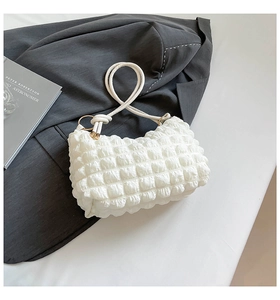 Close-up of white bubble popcorn texture fabric on shoulder bag with knot strap detail