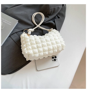 Detailed view of white pleated handbag texture with a smartphone for size reference