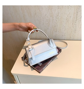 Detail of silver metallic crossbody bag with magnetic buckle and adjustable shoulder strap