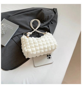 Detailed view of white bubble textured handbag with gold hardware and shoulder strap