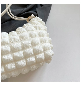Close-up of white bubble texture fabric on a stylish shoulder bag with golden metal buckle