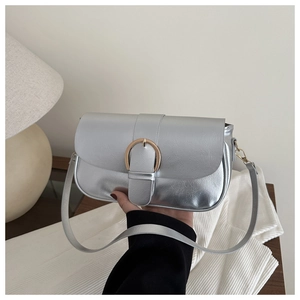Détail du sac à rabat argenté avec boucle fer à cheval dorée en cadre de vie