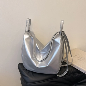 Detail of silver metallic large tote bag showing shiny pleated texture and long strap