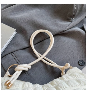 Detail of white textured bubble bag showing knotted strap and gold metal rings