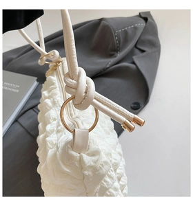Close-up of white bubble pleated fabric texture with gold metal ring and zipper detail