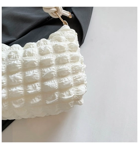 Detail of white bubble texture fabric with ruffled pattern and gold metal hardware