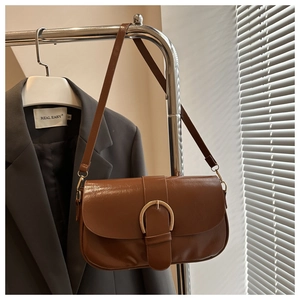 Détail du sac en cuir marron avec une boucle dorée vintage en forme de fer à cheval