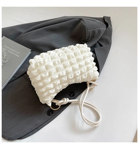 Detail of white popcorn texture shoulder bag with rope strap and gold metal rings