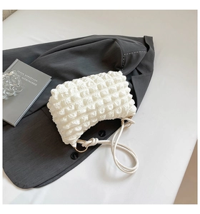 Detailed close-up of white pleated popcorn texture fabric and braided rope strap on handbag