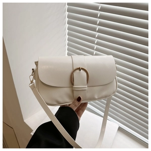 Gros plan sur la texture du cuir PU blanc et la boucle dorée semi-circulaire du sac
