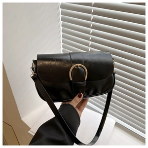 Détail d'un sac sous les aisselles noir rétro avec boucle métallique dorée semi-circulaire